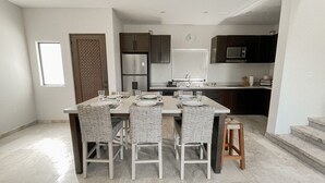 Una cocina moderna con armarios oscuros, un refrigerador de acero inoxidable, un microondas y un lavamanos.