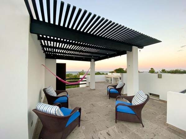 Eine Dachterrasse mit Korbmöbeln und einer Hängematte, mit Blick auf eine schöne Aussicht.