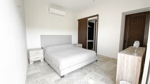 Un dormitorio con cama, mesitas de noche, armario y tocador con espejo.