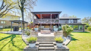 A modern two-story house with a covered patio, stone steps, and potted plants. -  Modern Lakefront Property
 (Hot Springs)
