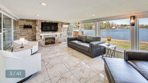 A spacious living area with a stone fireplace, leather sofas, and a large TV screen. -  Modern Lakefront Property
 (Hot Springs)