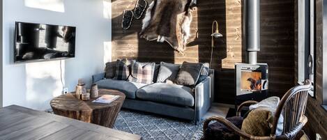 Un salon moderne avec un grand mur en bois, un canapé, une table basse et une cheminée.