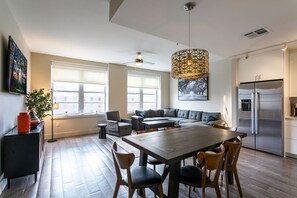 Relax in a spacious living area with a dining table, sofa, and armchair, and enjoy a fully equipped kitchen with a refrigerator and oven.