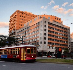 Un tram rosso su una via cittadina, con un palazzo a più piani sullo sfondo.