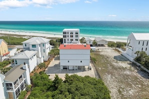 Un quartier résidentiel situé sur la côte, avec des bâtiments blancs, une plage et une vue dégagée sur l’océan.