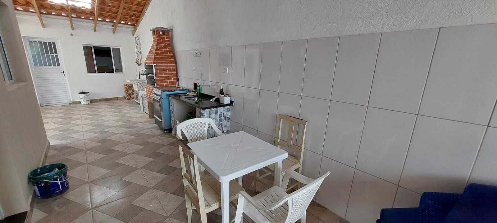 Een keuken met een betegelde spatwand, een bakoven en een eetgedeelte met een tafel en stoelen.