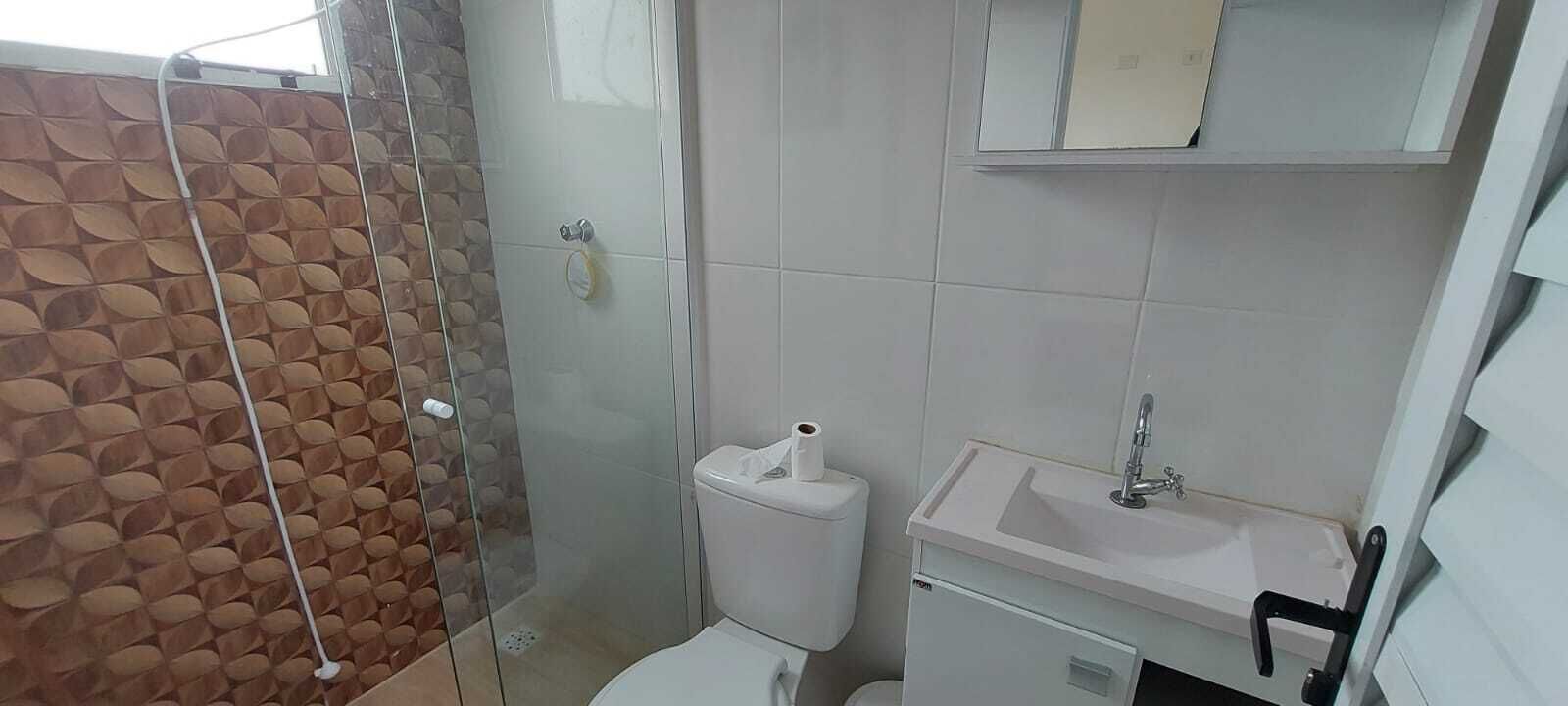 Un bany amb plat de dutxa, vàter, rentamig i un armari damunt del rentamig.
