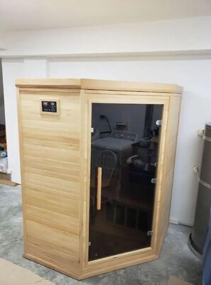 Relax in a serene sauna with a control panel and comfortable seating area.