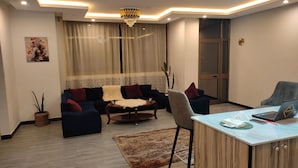 A modern living room with a sofa, coffee table, and a desk with a laptop. - Addis Hill  (Addis Ababa)