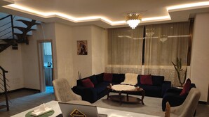 A modern living room with a sofa, coffee table, and a laptop on a marble table. - Addis Hill  (Addis Ababa)