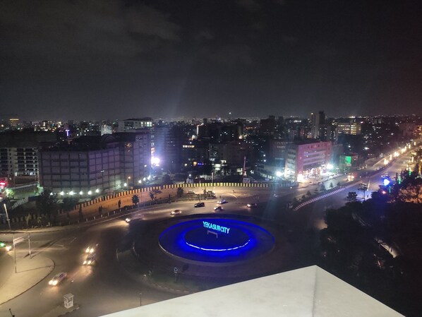 A nighttime cityscape with a roundabout and illuminated buildings.