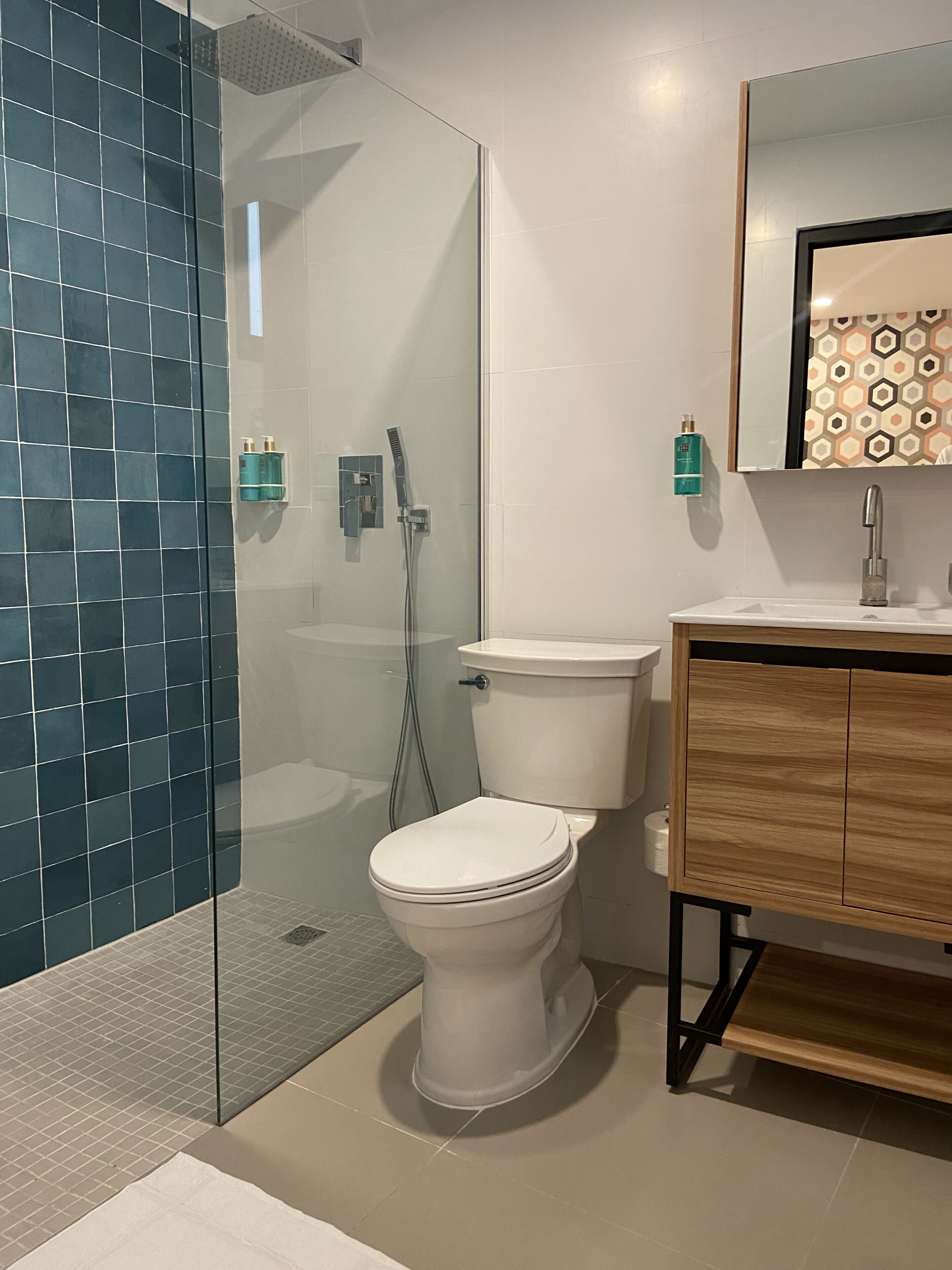 A modern bathroom with a glass-enclosed shower, a white toilet, and a wooden vanity with a mirror.