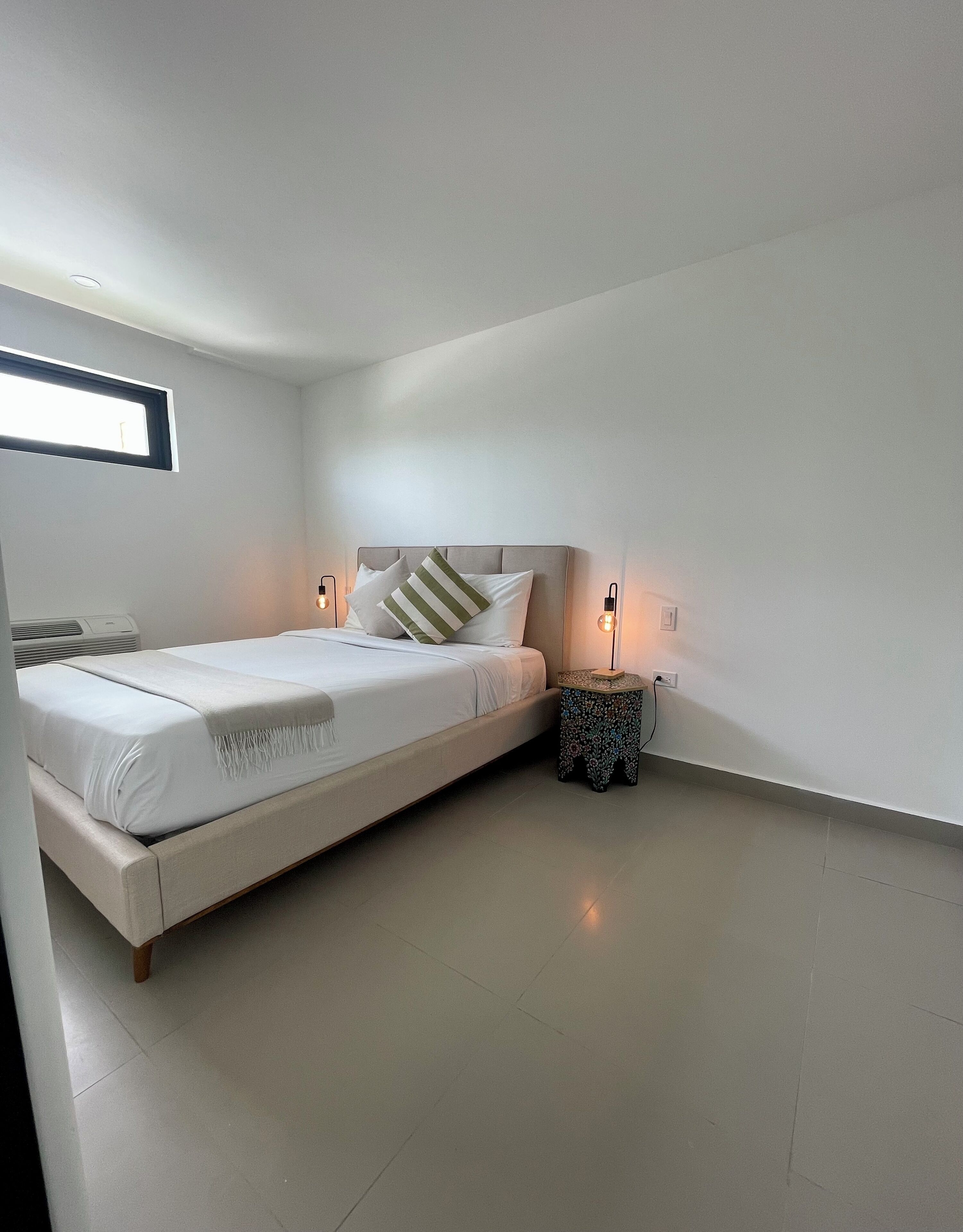 Una camera da letto moderna con un letto, comodini e un piccolo oggetto decorativo.