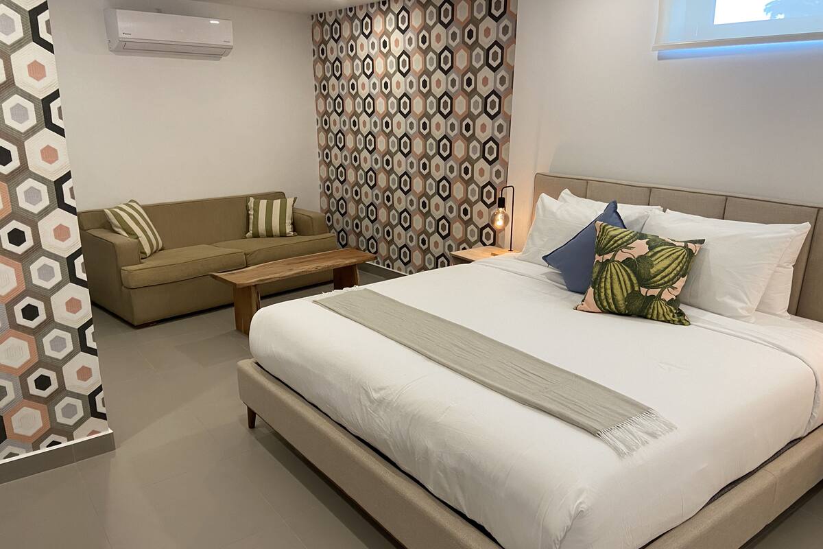 A modern bedroom with a large bed, a sofa, and a small table.