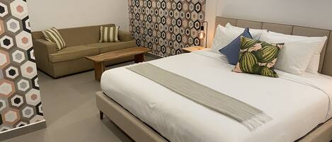 A modern bedroom with a large bed, a sofa, and a small table.