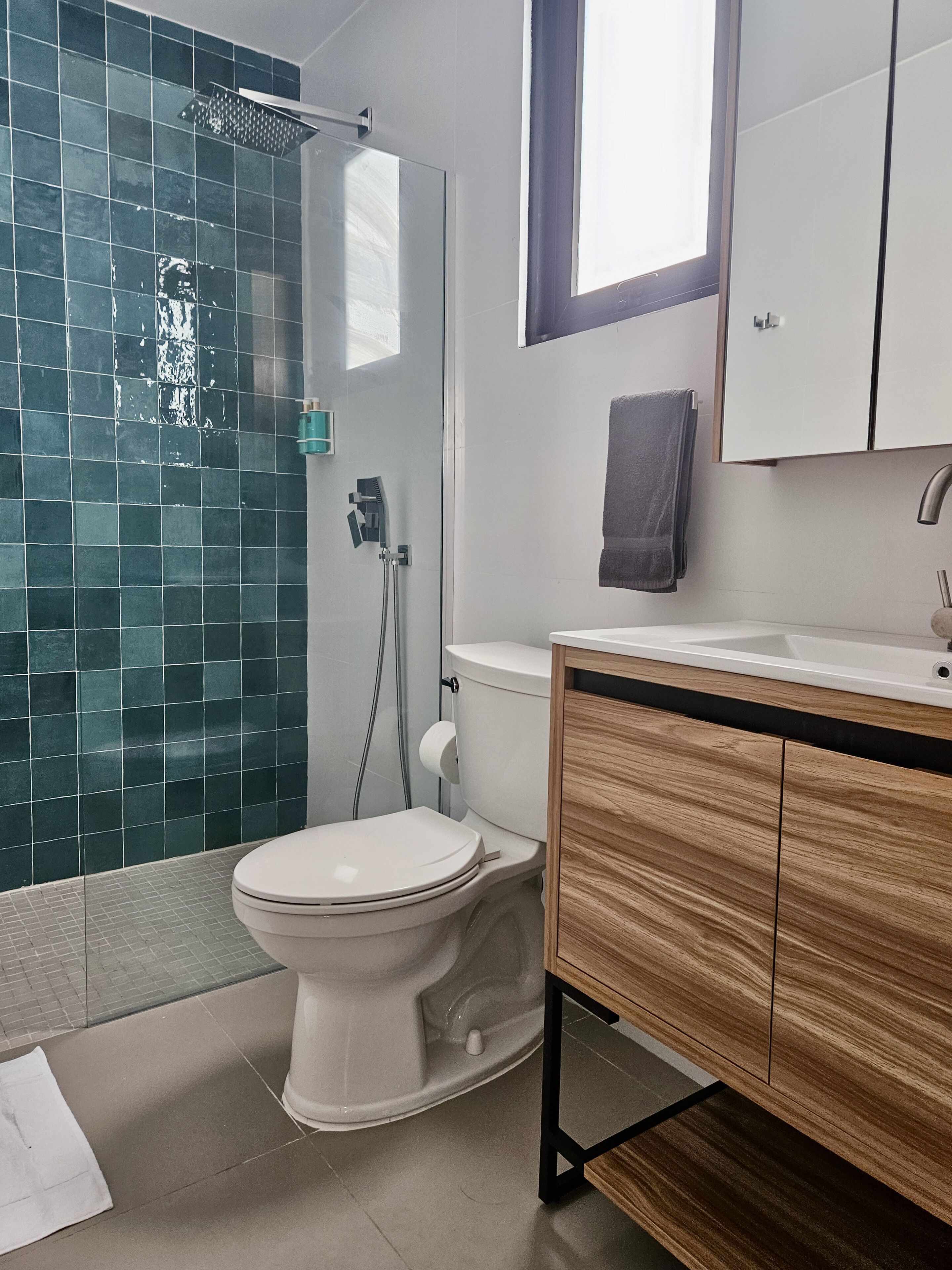 A modern bathroom with a glass shower enclosure, a white toilet, and wooden cabinetry.