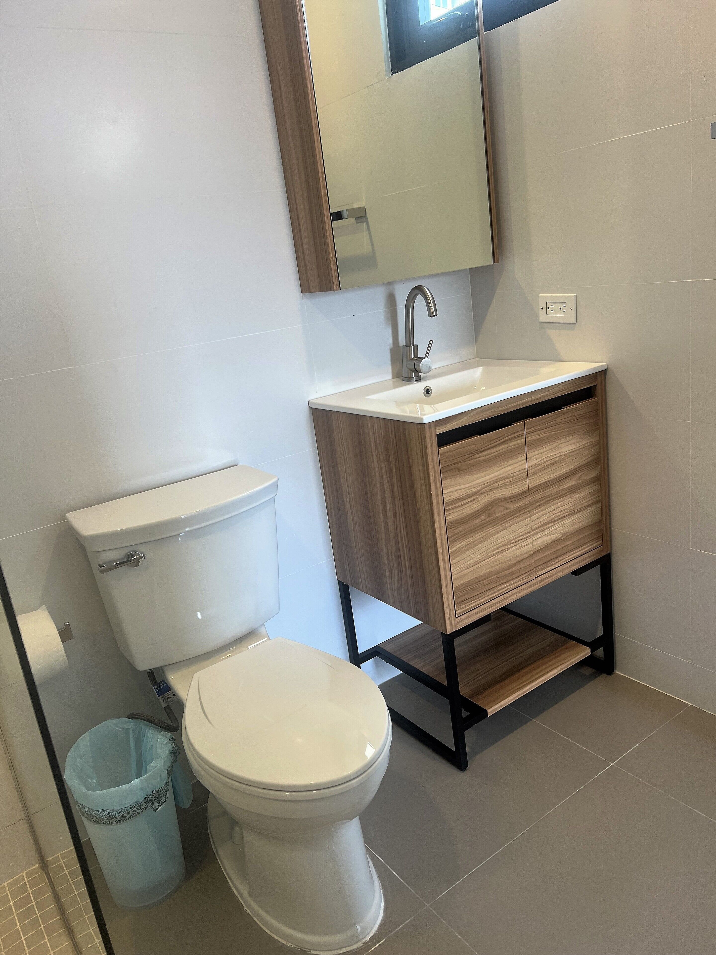 A modern bathroom with a toilet, sink, and mirror.