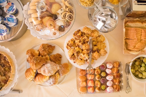 A buffet with various food items including pastries, fruits, and condiments. - La Petite Maison (Tresnuraghes)