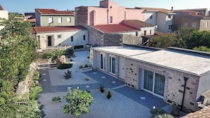 Une cour intérieure avec un bâtiment moderne doté de grandes fenêtres et d’une façade en pierre.