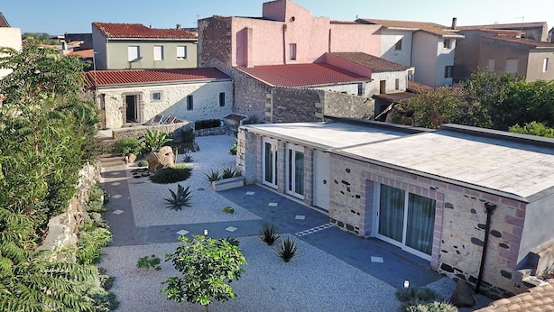 Une cour intérieure avec un bâtiment moderne doté de grandes fenêtres et d’une façade en pierre.