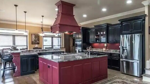 A spacious kitchen with a large island, stainless steel appliances, and dark cabinetry.