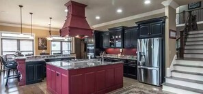 Una cocina amplia con una isla grande, electrodomésticos de acero inoxidable y muebles oscuros.