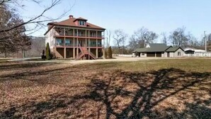 A two-story building with a red roof, a covered porch, and a fenced yard.
