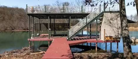 A wooden dock with a metal staircase leading to a covered area by a body of water.