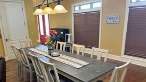 A dining area with a dark wooden table, white chairs, and a vase of flowers.
