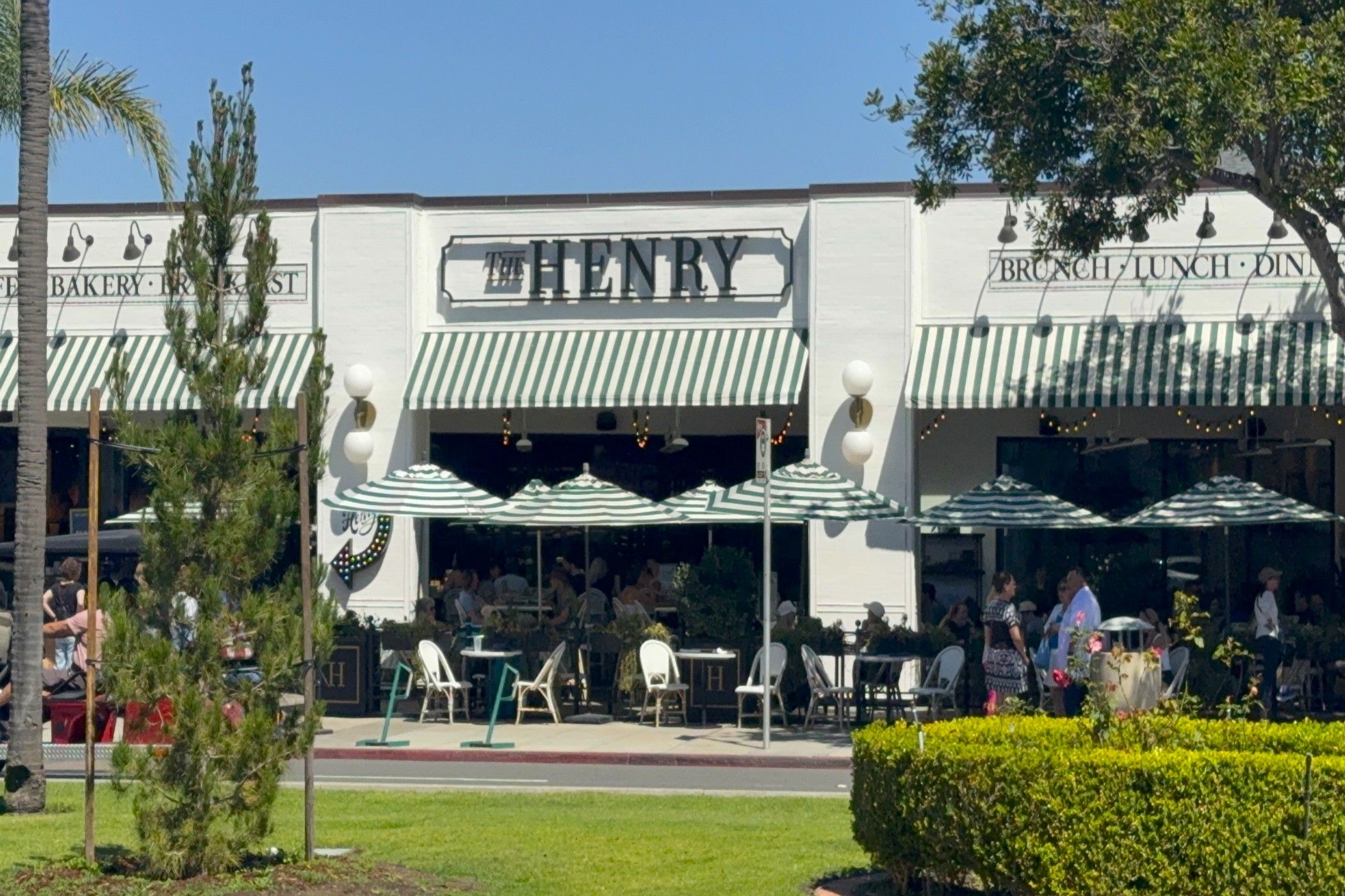 Un restaurant appelé « The Henry », doté d’une terrasse et d’un auvent à rayures vertes.