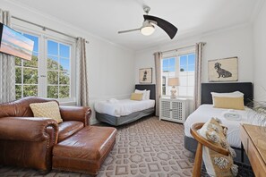 A hotel room with a leather sofa, two beds, a ceiling fan, and artwork on the walls. - Walk to Beaches, Dining & Everything Coronado Has to Offer | Coronado Crown Vi (Coronado)