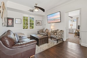 A living room with a leather couch, patterned armchairs, a coffee table, and a TV mounted on the wall. - Walk to Beaches, Dining & Everything Coronado Has to Offer | Coronado Crown Vi (Coronado)