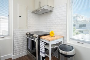 A compact kitchen with white subway tile walls, a stainless steel range, a built-in oven, a wooden countertop, and a window with blinds. - Walk to Beaches, Dining & Everything Coronado Has to Offer | Coronado Crown Vi (Coronado)