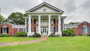 A large, symmetrical building with a central entrance flanked by two wings, each with a brick facade and white trim. - Jenny’s Southland Homestead, LLC (Bowling Green)