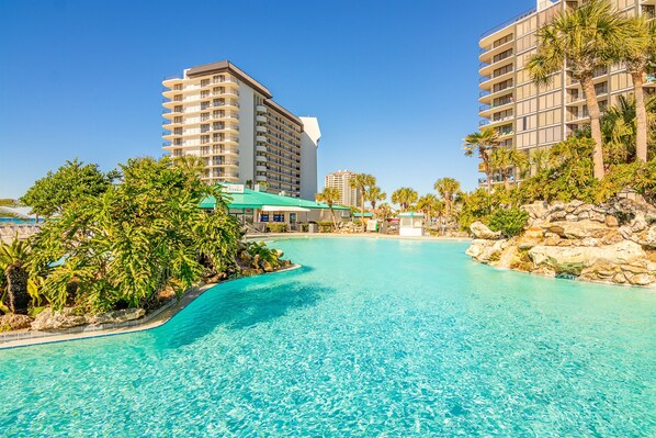 Un hotel con una piscina grande, rodeado de palmeras y un paisaje rocoso.