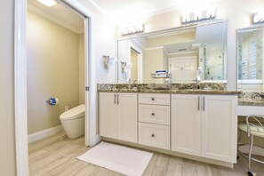 A bathroom with a toilet, a sink with a mirror, and a vanity with drawers.