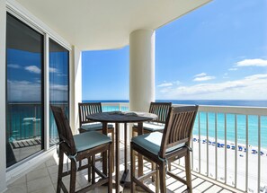 A balcony with a table and chairs, a view of the ocean, and a pool area. - Beautifully Updated Silver Beach Towers 3-Bedroom Condo (Destin)