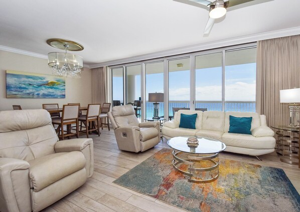 A spacious living room with a large window, a ceiling fan, and a dining area.
