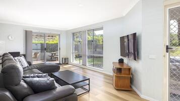 A modern living room with a sectional sofa, a coffee table, and a TV mounted on the wall.