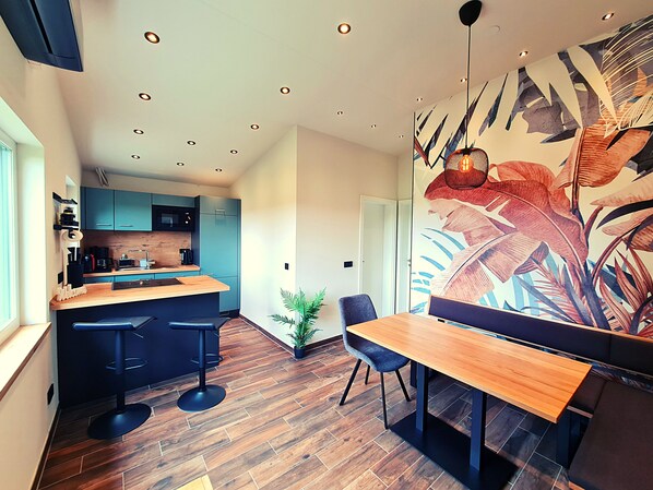 Eine moderne Küche mit blauen Schränken, einer Holz Arbeitsplatte und einer Bar mit Hockern.