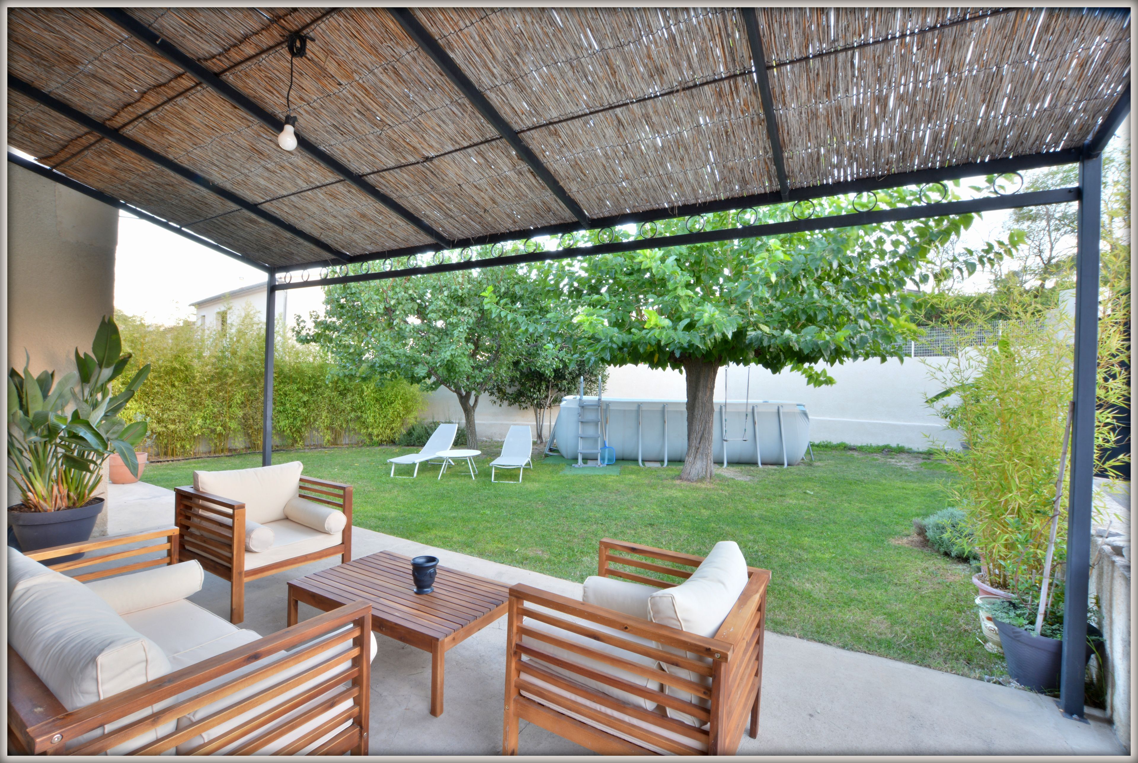 Une terrasse extérieure avec des meubles en bois, une table et une plante en pot.