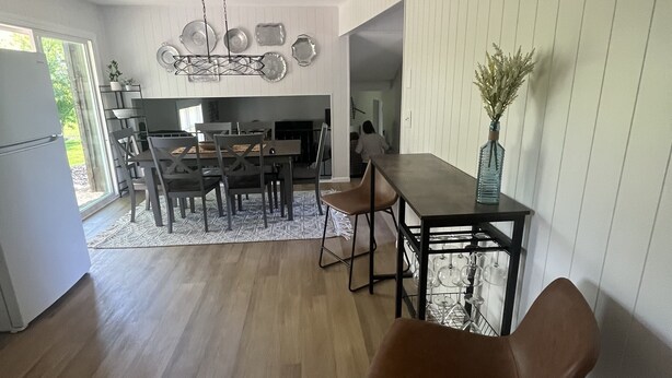A modern kitchen with white cabinetry, a dining area with a wooden table and chairs, and a visible refrigerator. - Remodeled Modern 4BR Avon Home with 3 Living Rooms on Large Private Lot/Farm (Avon)