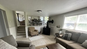A living room with a sofa, a coffee table, and a fireplace. There is a staircase leading to another room. - Remodeled Modern 4BR Avon Home with 3 Living Rooms on Large Private Lot/Farm (Avon)