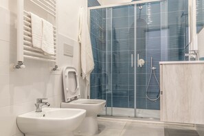 A modern bathroom with a glass shower enclosure, two sinks, and a towel rack. - Casina Rossa (Naples)