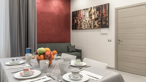 A dining area with a table set for four, a fruit bowl, and a painting on the wall. - Casina Rossa (Naples)