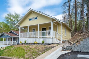 A yellow house with a porch, white railings, and a stone retaining wall. - NEW! UPTOWN Cottages - 2bed/1bath - new furnishings! (Hot Springs)
