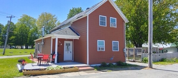 A red single-story house with a front porch, a small deck, and a fenced yard.