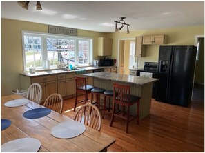 A kitchen with wooden cabinets, a black refrigerator, and a dining area with a wooden table and chairs.