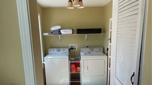 Une buanderie équipée de deux machines à laver, d’un sèche-linge et d’une étagère où sont pliées les serviettes.