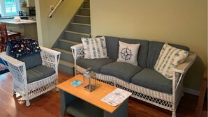 Un salon avec des meubles en osier, une table basse et un escalier.